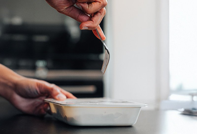 Er worden gaatjes in een maaltijdverpakking geprikt